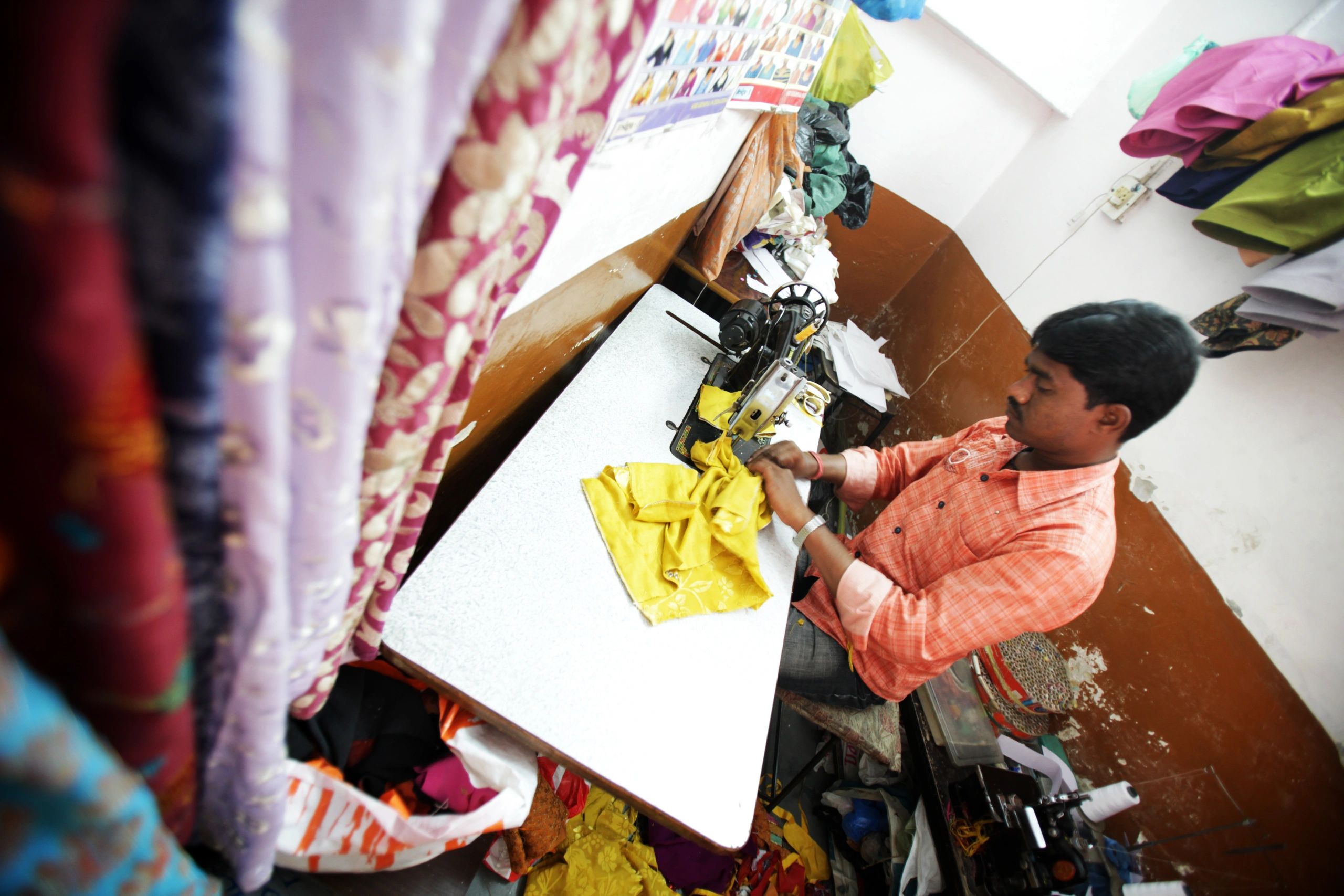 Tailor stitching garments in an Indian workshop